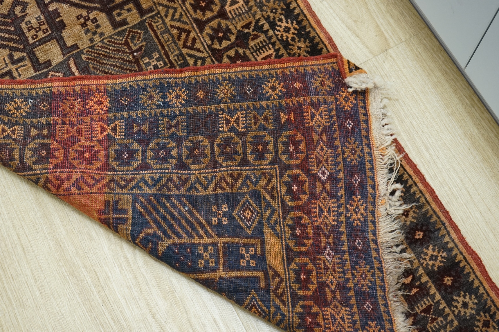 A small brown and red ground rug, 86cm wide